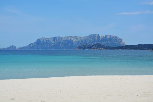 plage de sable blanc, eau turquoise et montagne